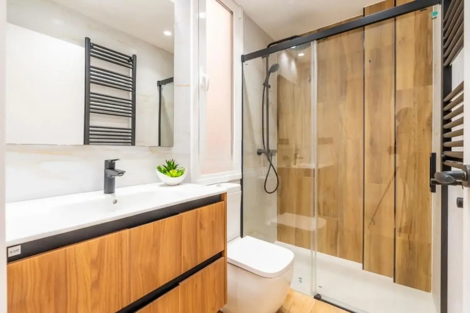 Baño reformado con mueble de madera y mampara corredera en Comarruga