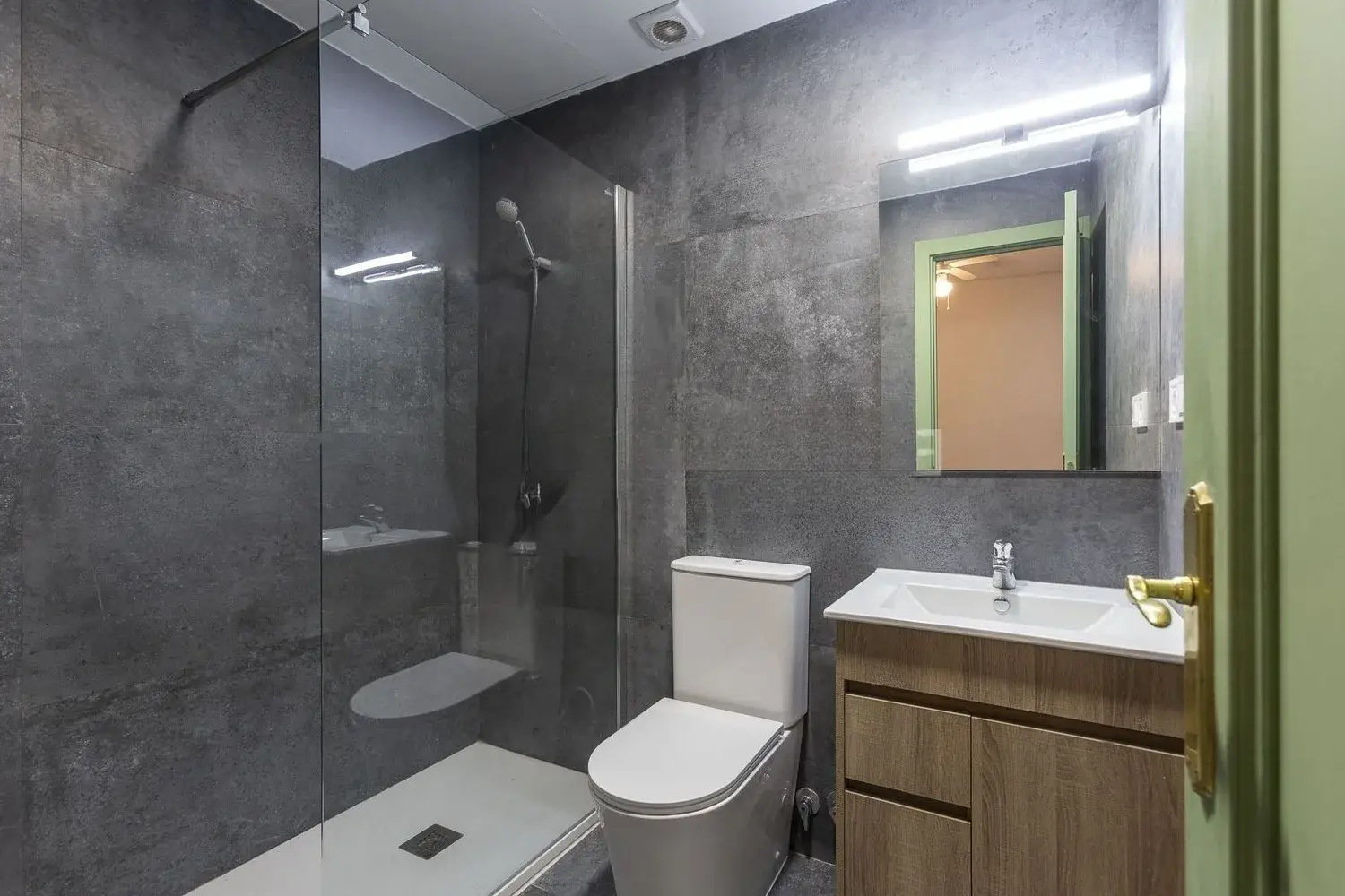 Baño con plato de ducha y revestimiento gris reformado en Comarruga